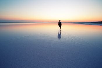 Salt lake Tuz with man leaving at sunset. Silhouette. Summer landscape. Anatolia, Turkey. Salt lake Tuz with man leaving at sunset
