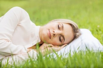 Young woman sleeping on soft pillow in fresh spring grass. Woman sleeping on pillow in grass
