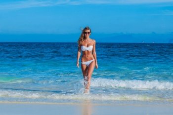 Pretty smiling girl in bikini walking at tropical sea beach. Pretty girl at the beach