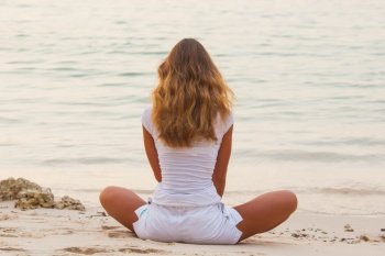 Woman in lotus yoga pose at sunrise on the beach. Yoga at sunrise