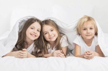 Three happy smiling children under blanket at home. Three children under blanket
