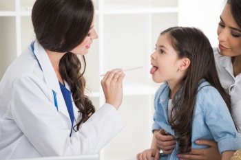 Little girl and her mother at pediatrician office. Doctor examine child’s throat. Doctor examine child’s throat