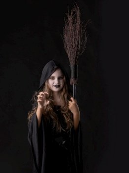 Girl in halloween evil angry witch costume grin snarl hold broom isolated on black background. Girl in halloween witch costume