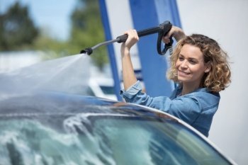 attractive woman washing automobile at manual car wash