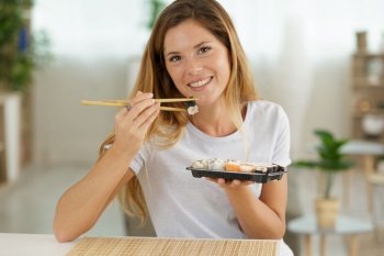beautiful young woman with sushi roll at home