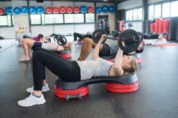 group of people excercising with bars in gym