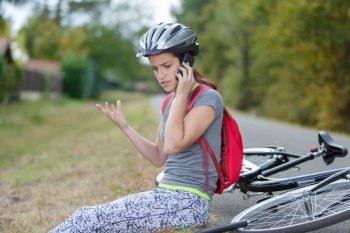 woman with bicycle puncture gesticulating while using phone