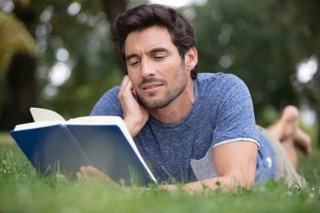 young man reading a book in the park