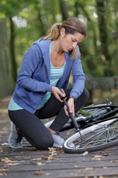 young woman pumping up tire tyre with bike bicycle pump