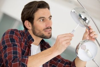 man fitting a new bulb in a lamp