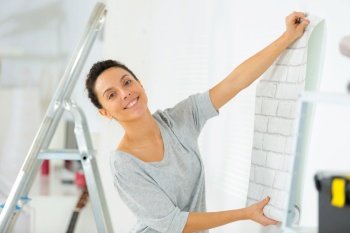 woman unrolling a wall paper on the wall