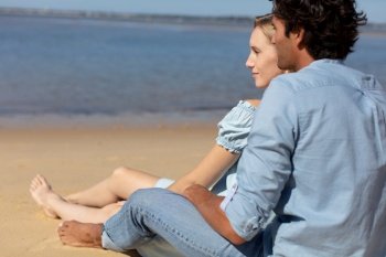 beautiful young couple sitting on sandy coast