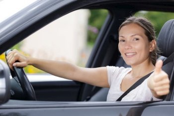 portrait of female driving holding thumbs up