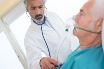 senior man inhaling through oxygen mask in clinic