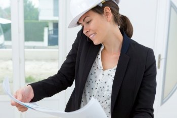beatiful woman engineer with plans papers on building site