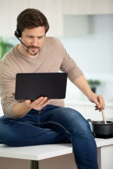 man wearing headset looking at computer while cooking