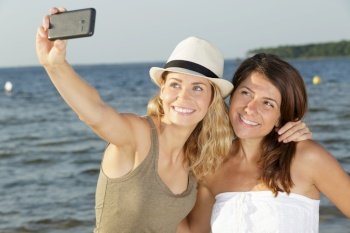 two female friends taking selfie with the sea behind them