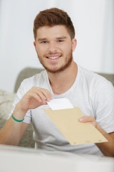 young man taking letter from envelope