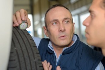 two mechanics car tyre pressure measuring