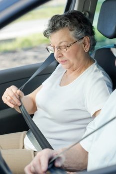 lovely senior woman fasten security belt in a car