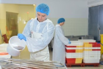 young worker in white coat working on dairy factory