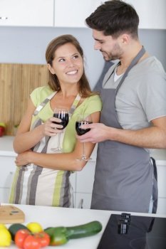 happy couple standing in kitchen enjoying a glass wine