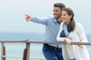 couple by a railing looking and pointing into the distance