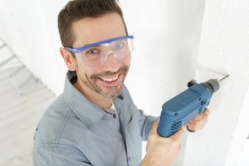 happy male builder drilling a wall