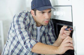 man fixing an oven in kitchen