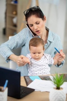 stressed mother with baby working in home office