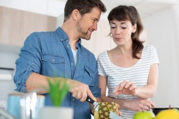 young couple making smoothie in kitchen