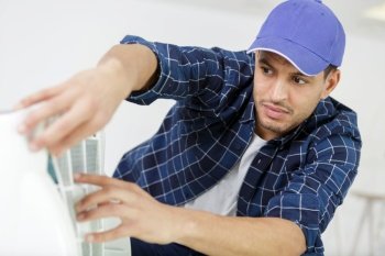 male technician repairing air conditioner