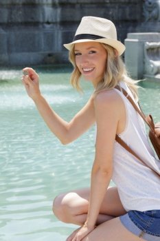happy woman tourist holding coin to throw in fountain