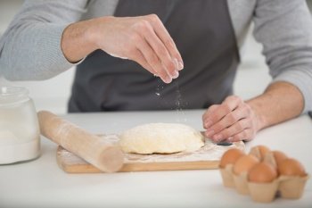 close up of male hands kneading dough