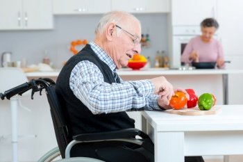 senior couple cooking together - man disabled on wheelchair