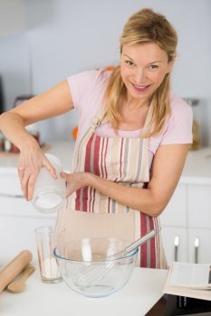 mature beautiful woman pouring sugar to cook sweet dessert