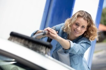 young attractive blonde woman washing the dirty car