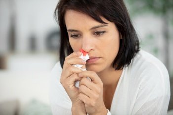 woman with nosebleed sitting in living room