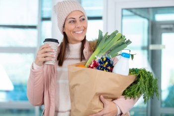 woman carrying groceries and a takeaway coffee