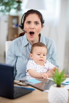 esperate mother working at laptop with baby