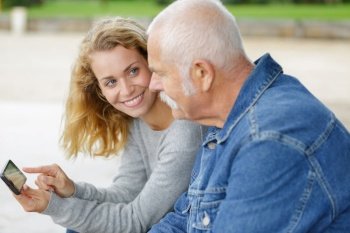 elderly man looking at smartphone with his adult daughter