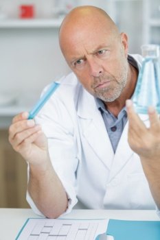 senior scientist analysing flask and test-tube