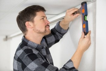 man checking the installation with level on wall