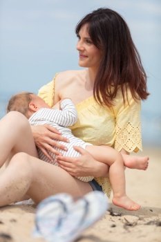 mother breastfeeding baby on the beach
