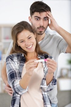 excited wife and not ready worried man with pregnancy test