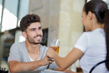 young couple in bar chinking glasses