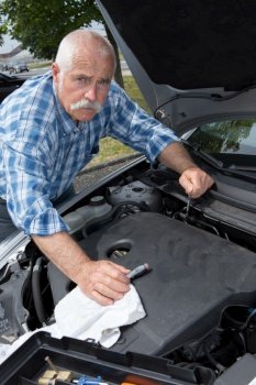 older man cleaning car engine with microfiber