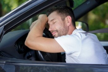 man sleep in car while driving on the road