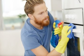 man spraying product to clean oven