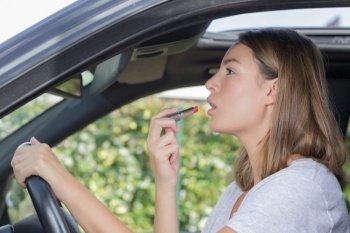 woman putting on lipstick in a car
